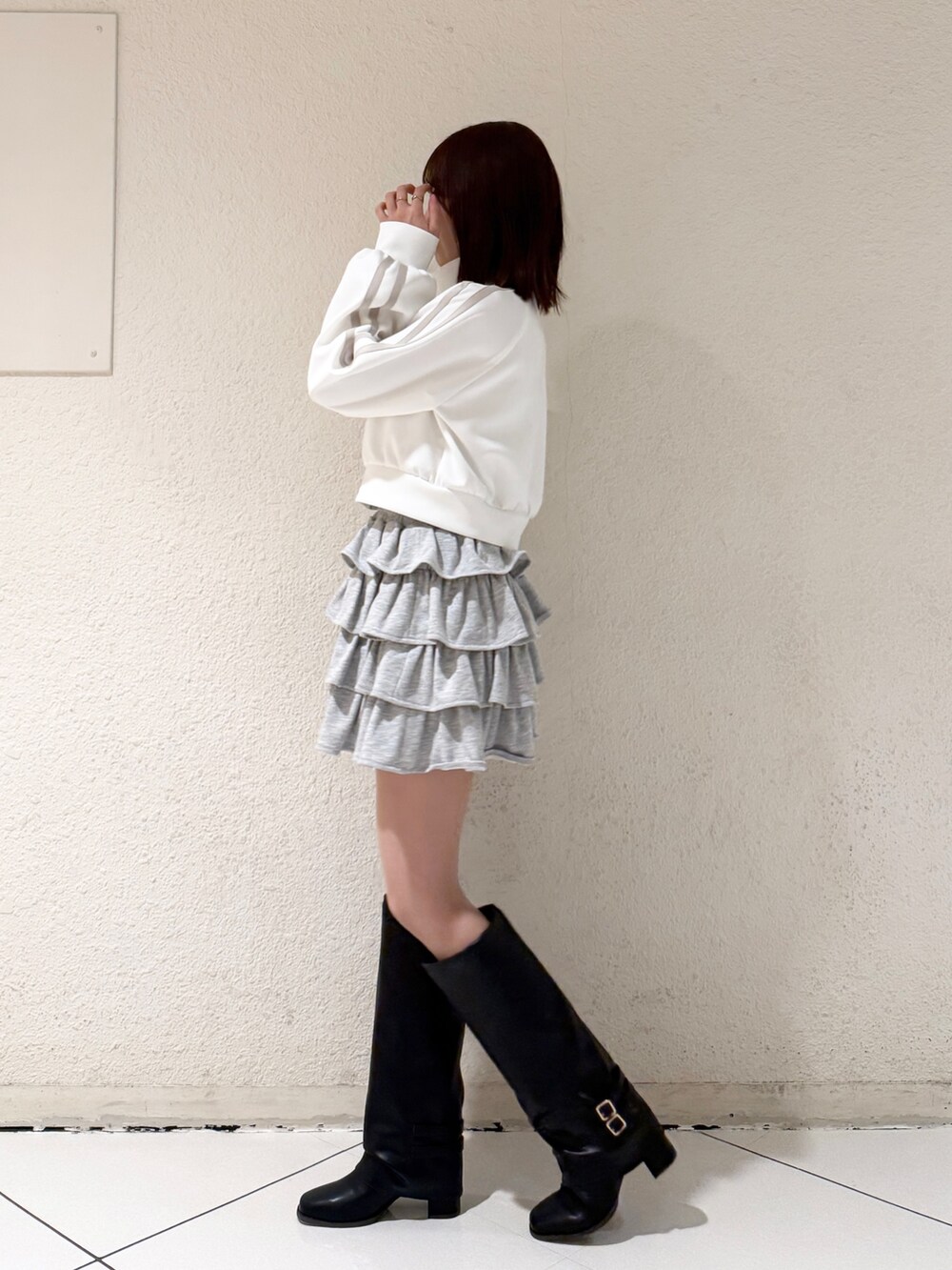 ブラック系のブーツ、グレー系のスカート、ホワイト系のその他アウターを着用したレディースの春コーディネートの3枚目の写真
