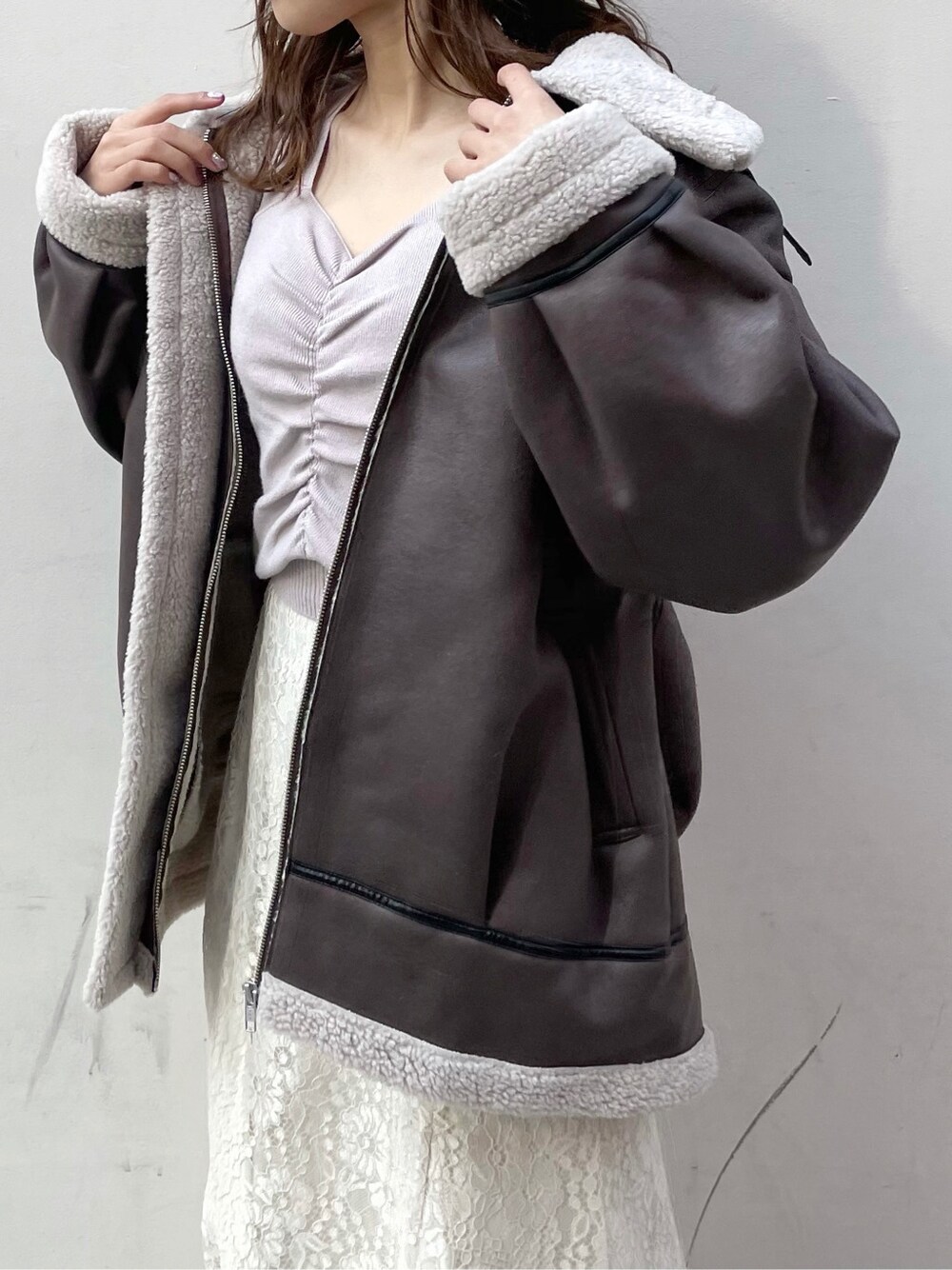 パープル系のニット/セーター、ホワイト系のブーツ、ホワイト系のスカートを着用したレディースの冬コーディネートの4枚目の写真