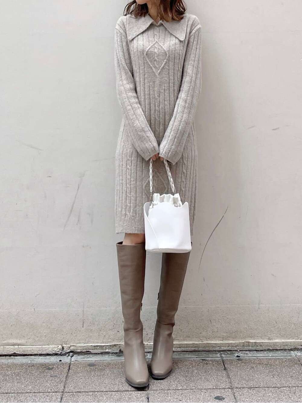 グレー系のワンピース、ホワイト系のハンドバッグ、ベージュ系のブーツを着用したレディースの秋コーディネートの4枚目の写真