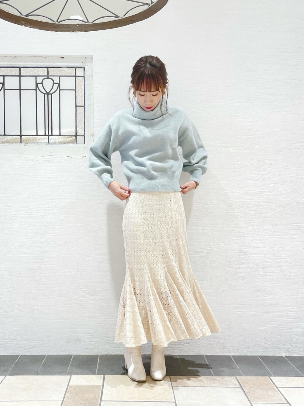 ホワイト系のスカート、ホワイト系のブーツ、ブルー系のニット/セーターを着用したレディースの冬コーディネートの2枚目の写真