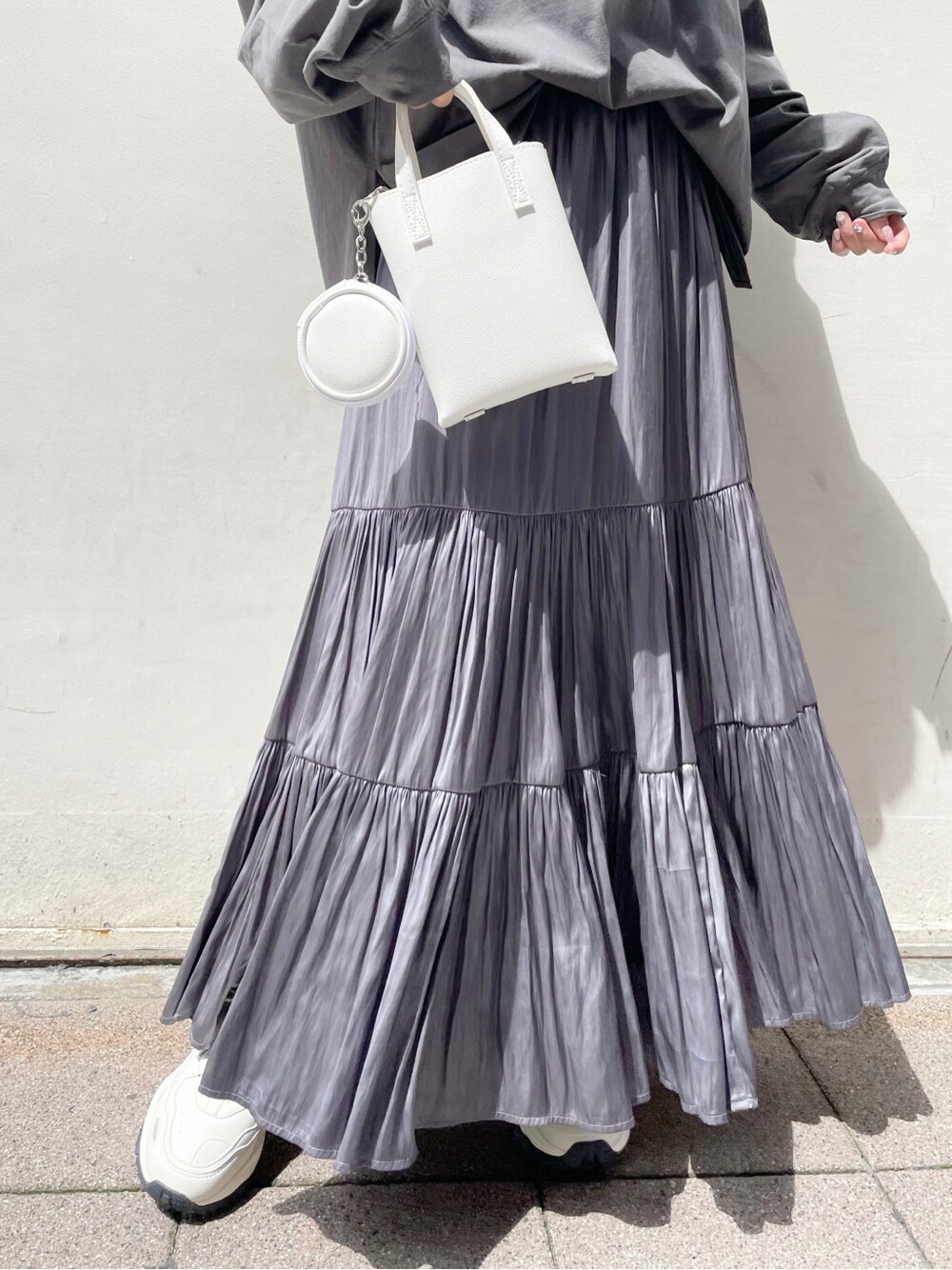 パープル系のスカート、ホワイト系のスニーカー、ホワイト系のハンドバッグを着用したレディースの春コーディネートの9枚目の写真