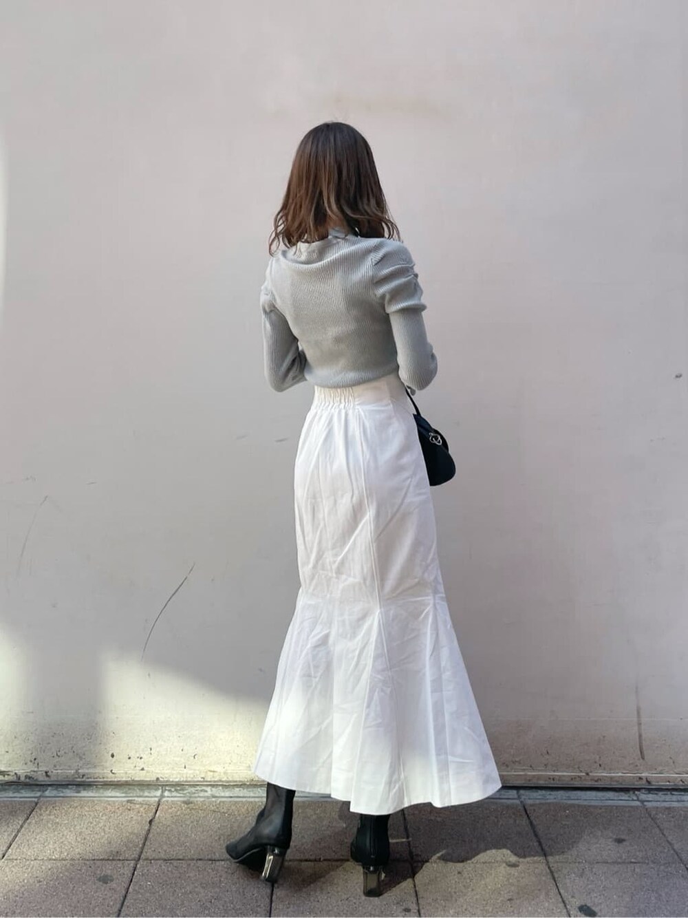 ホワイト系のスカート、ブラック系のブーツ、グリーン系のニット/セーターを着用したレディースの冬コーディネートの2枚目の写真