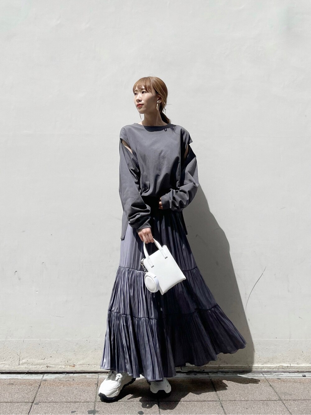 パープル系のスカート、ホワイト系のスニーカー、ホワイト系のハンドバッグを着用したレディースの春コーディネートの5枚目の写真