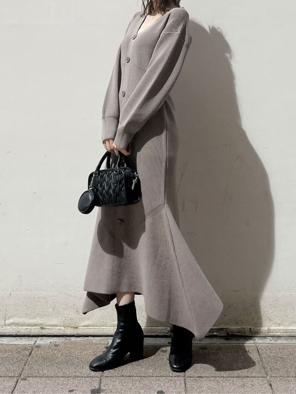 ブラック系のハンドバッグ、ホワイト系のブルゾン、ブラック系のブーツを着用したレディースの秋コーディネートの8枚目の写真