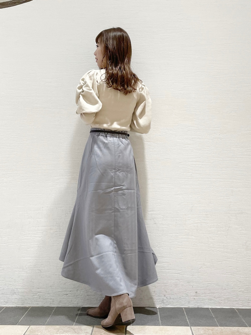 グレー系のスカート、ホワイト系のニット/セーター、ベージュ系のその他シューズを着用したレディースの冬コーディネートの2枚目の写真