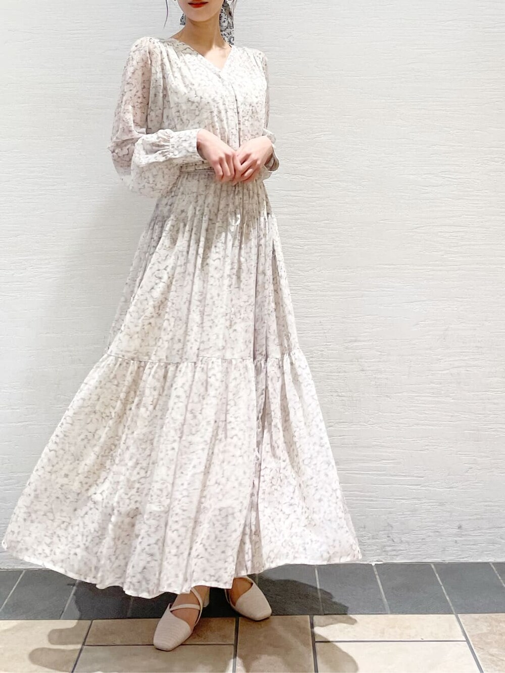 グレー系のトレンチコート、オレンジ系のワンピース、グレー系のニット/セーターを着用したレディースの冬コーディネートの2枚目の写真