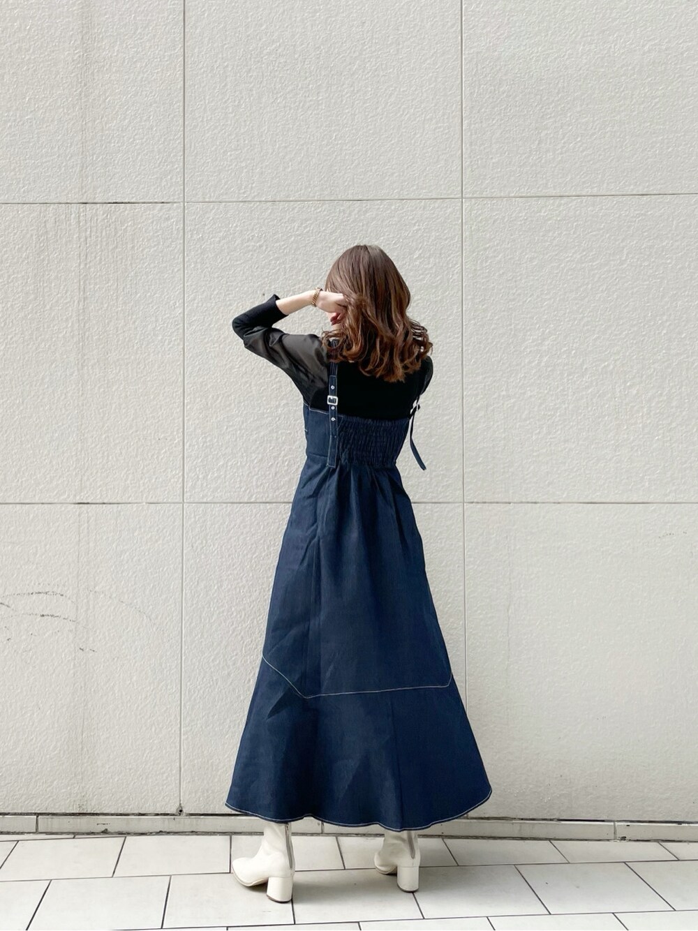 ホワイト系のブーツ、ブラック系のニット/セーター、ブルー系のワンピースを着用したレディースの冬コーディネートの2枚目の写真