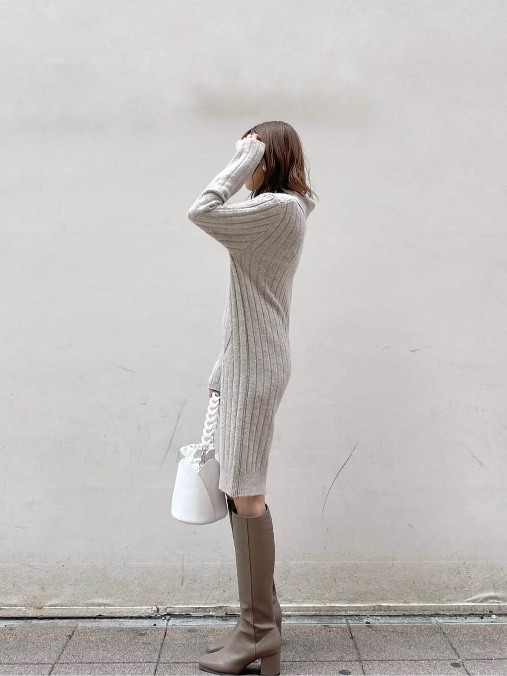 グレー系のワンピース、ホワイト系のハンドバッグ、ベージュ系のブーツを着用したレディースの秋コーディネートの2枚目の写真