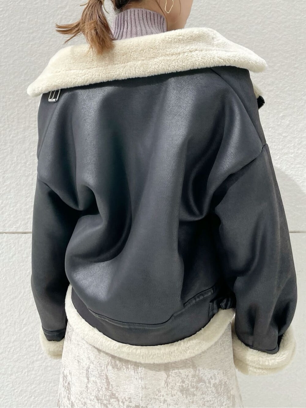 ブラック系のブルゾン、ベージュ系のスカート、ブラック系のブーツを着用したレディースの秋コーディネートの7枚目の写真