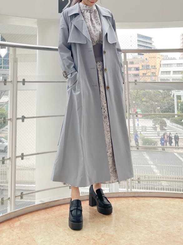 ブルー系のトレンチコート、グレー系のワンピース、ブラック系のローファーを着用したレディースの冬コーディネートの2枚目の写真