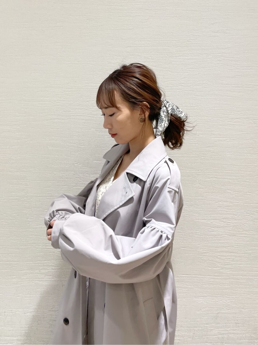 グレー系のトレンチコート、オレンジ系のワンピース、グレー系のニット/セーターを着用したレディースの冬コーディネートの7枚目の写真