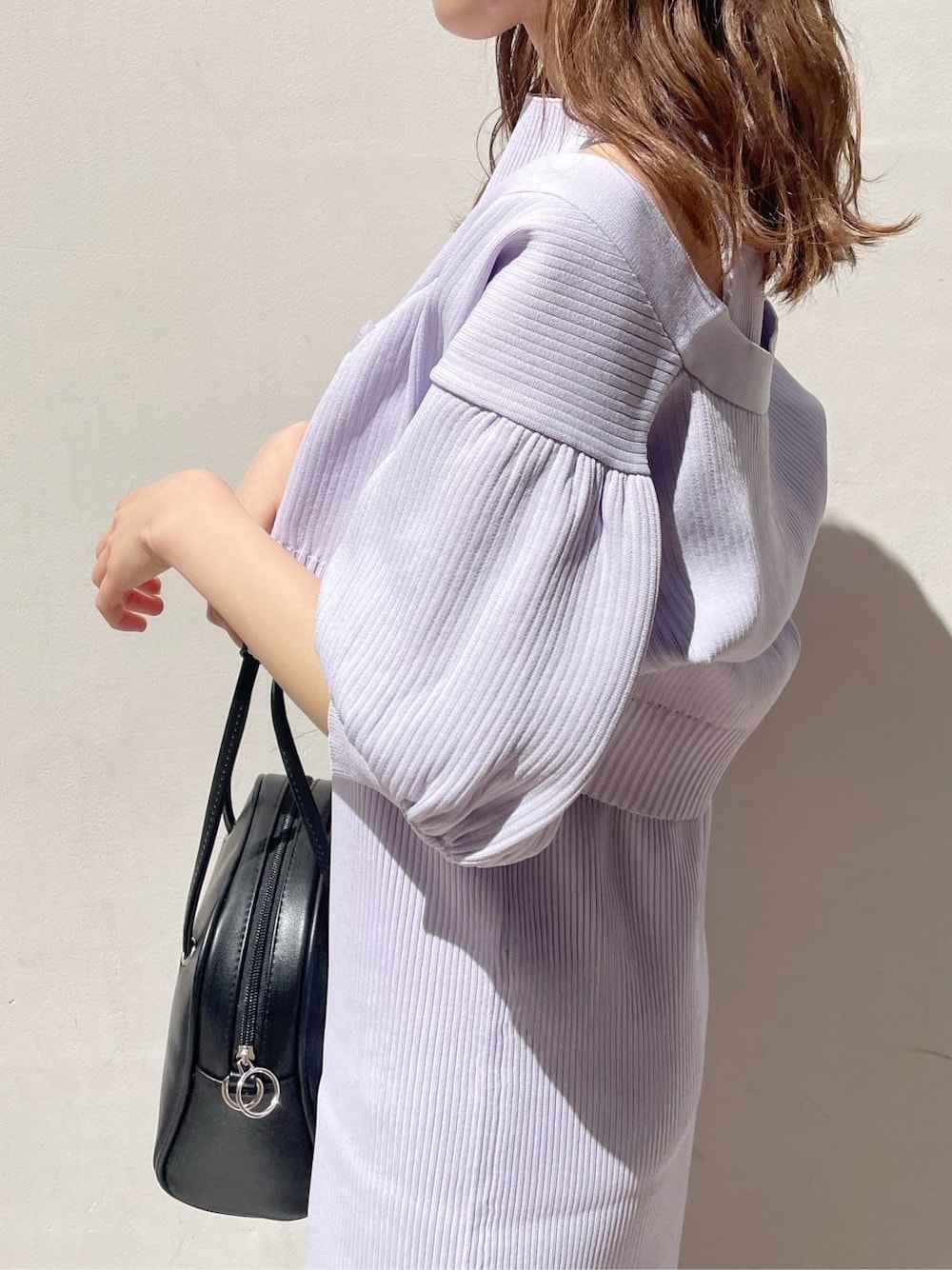 パープル系のワンピース、ブラック系のパンプス、ブラック系のハンドバッグを着用したレディースの春コーディネートの5枚目の写真