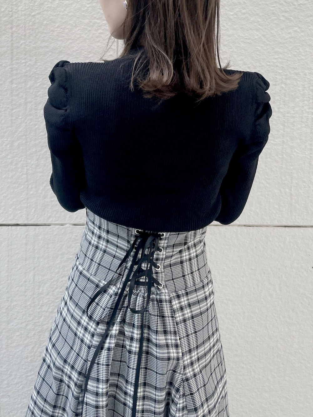 ブラック系のニット/セーター、グレー系のスカート、ブラック系のブーツを着用したレディースの秋コーディネートの5枚目の写真