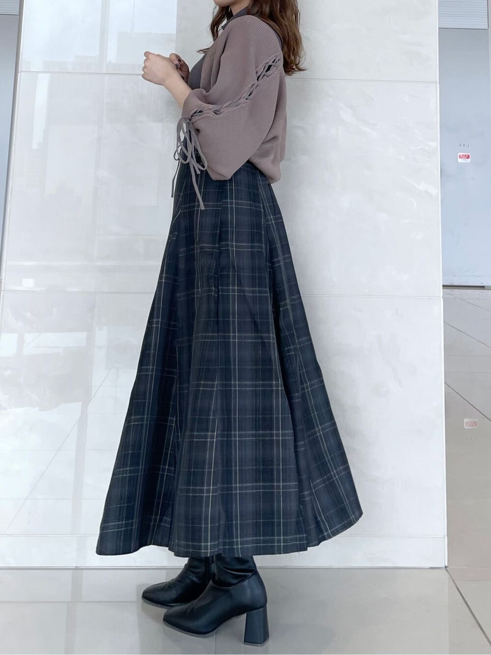 グレー系のワンピース、ブラック系のブーツ、ブラウン系のカーディガン/ボレロを着用したレディースの秋コーディネートの2枚目の写真