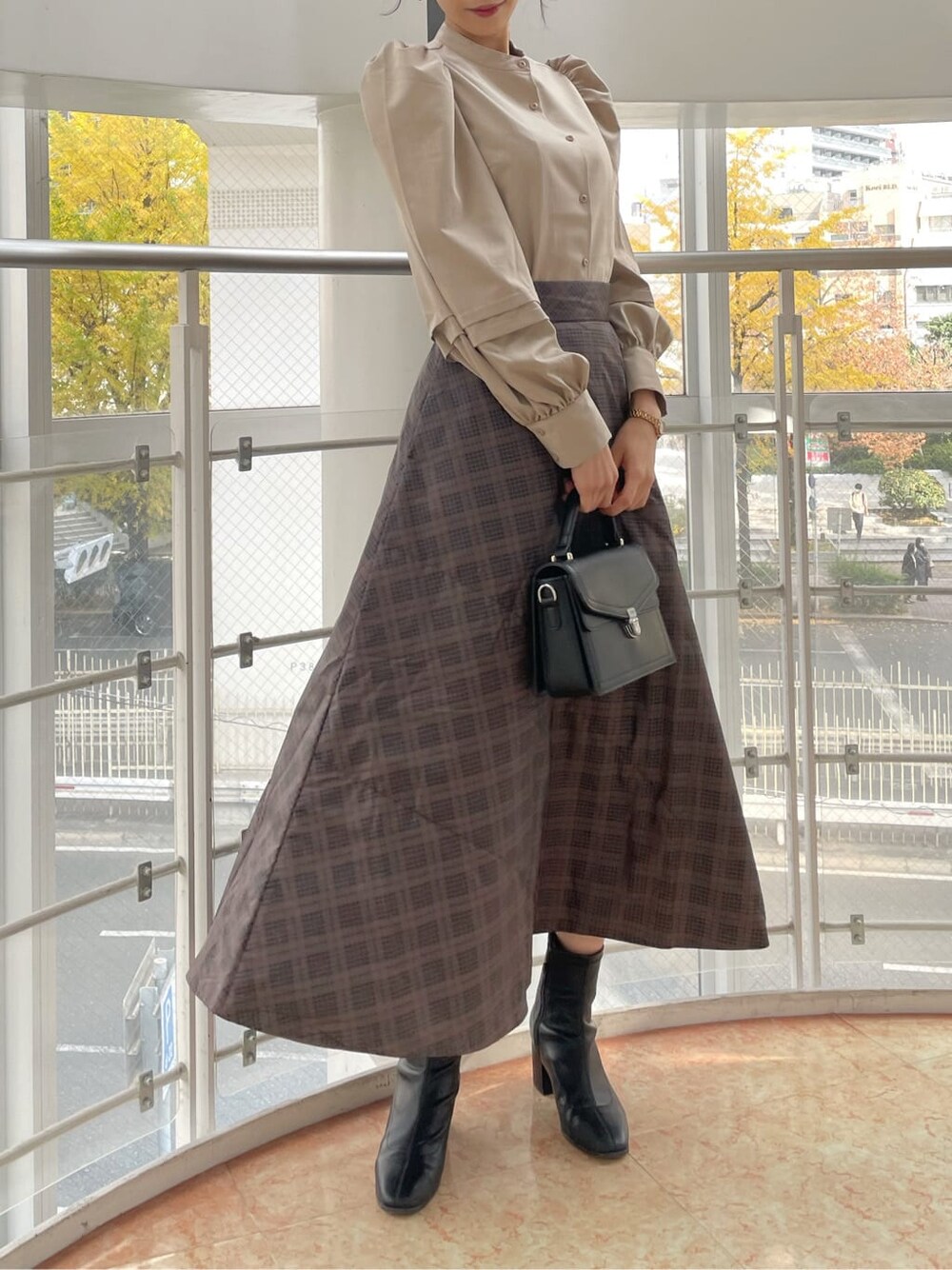 ブラック系のブーツ、ブラウン系のスカート、ベージュ系のシャツ/ブラウスを着用したレディースの冬コーディネートの7枚目の写真