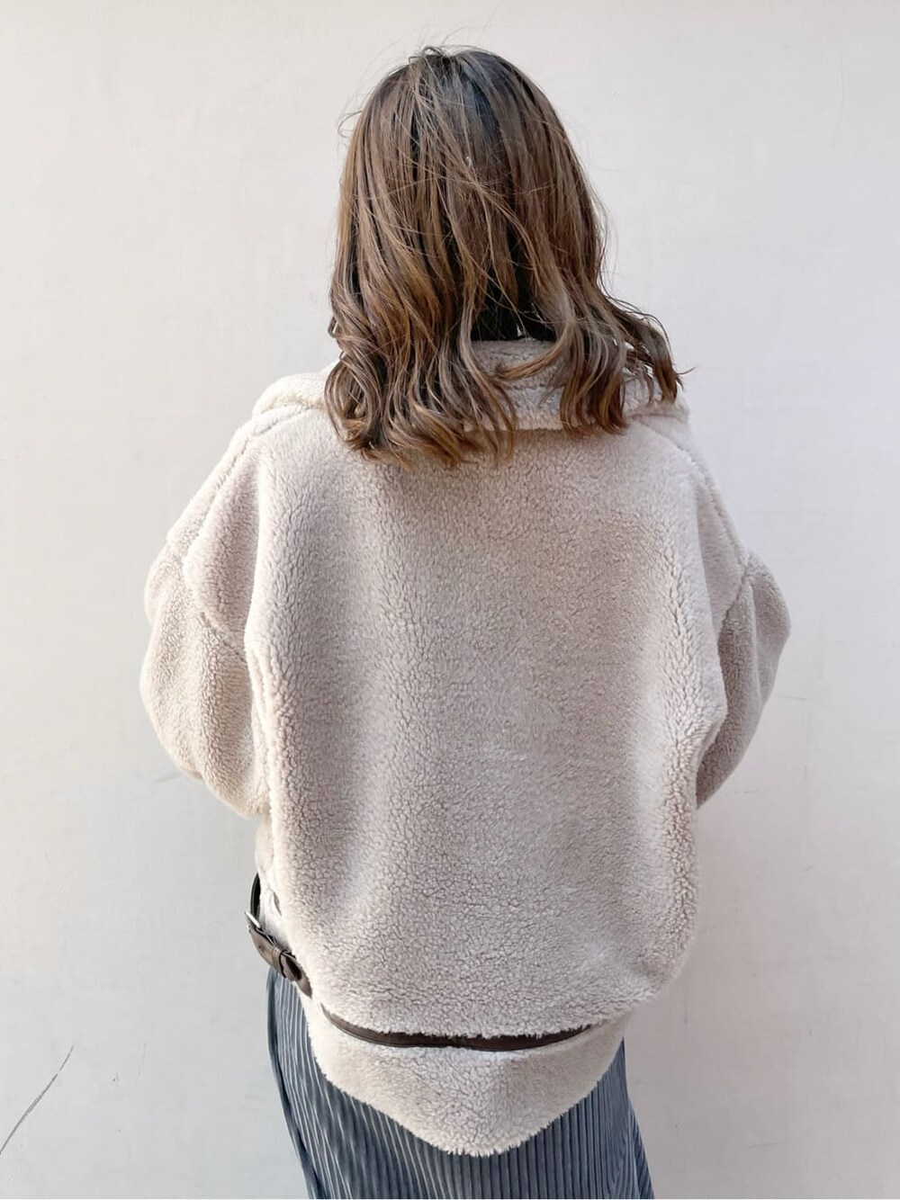 ベージュ系のブルゾン、ブラック系のブーツ、ブルー系のスカートを着用したレディースの秋コーディネートの4枚目の写真