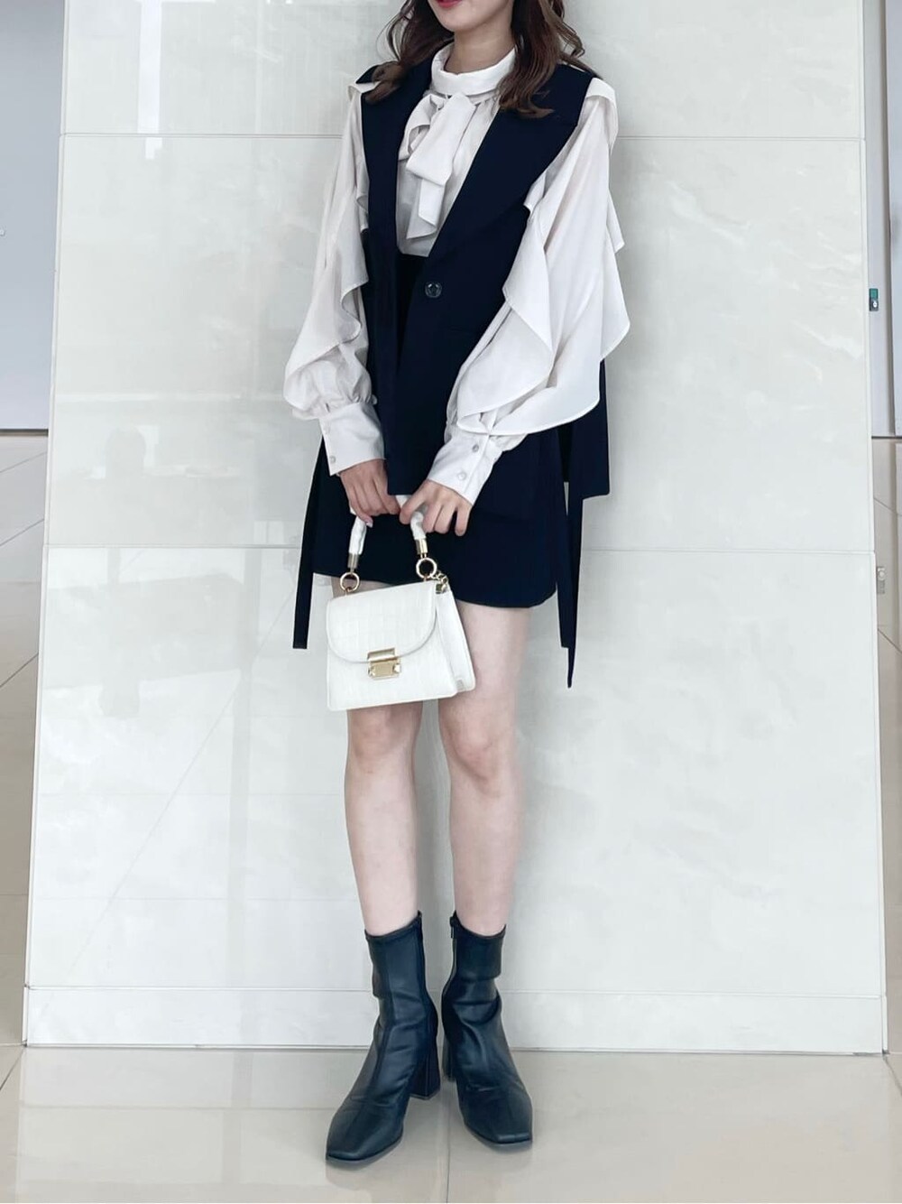 ホワイト系のシャツ/ブラウス、ブラック系のベスト、ブラック系のスカートを着用したレディースの秋コーディネートの2枚目の写真