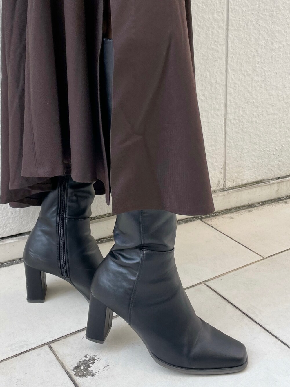 グレー系のニット/セーター、ブラウン系のスカート、ブラック系のブーツを着用したレディースの冬コーディネートの8枚目の写真