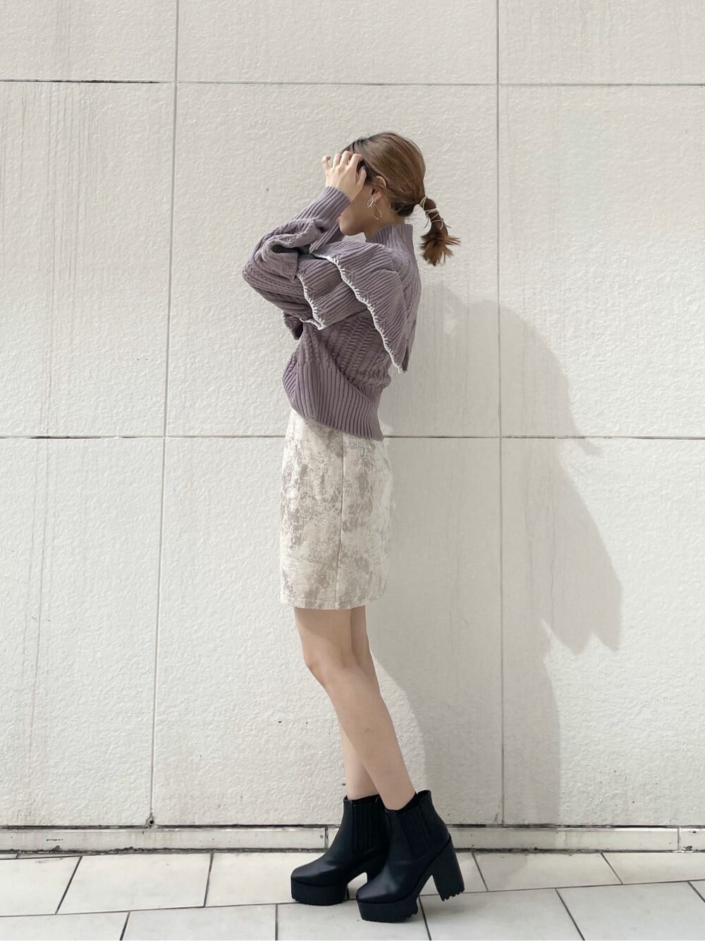 ベージュ系のスカート、ブラック系のブーツ、パープル系のニット/セーターを着用したレディースの秋コーディネートの2枚目の写真