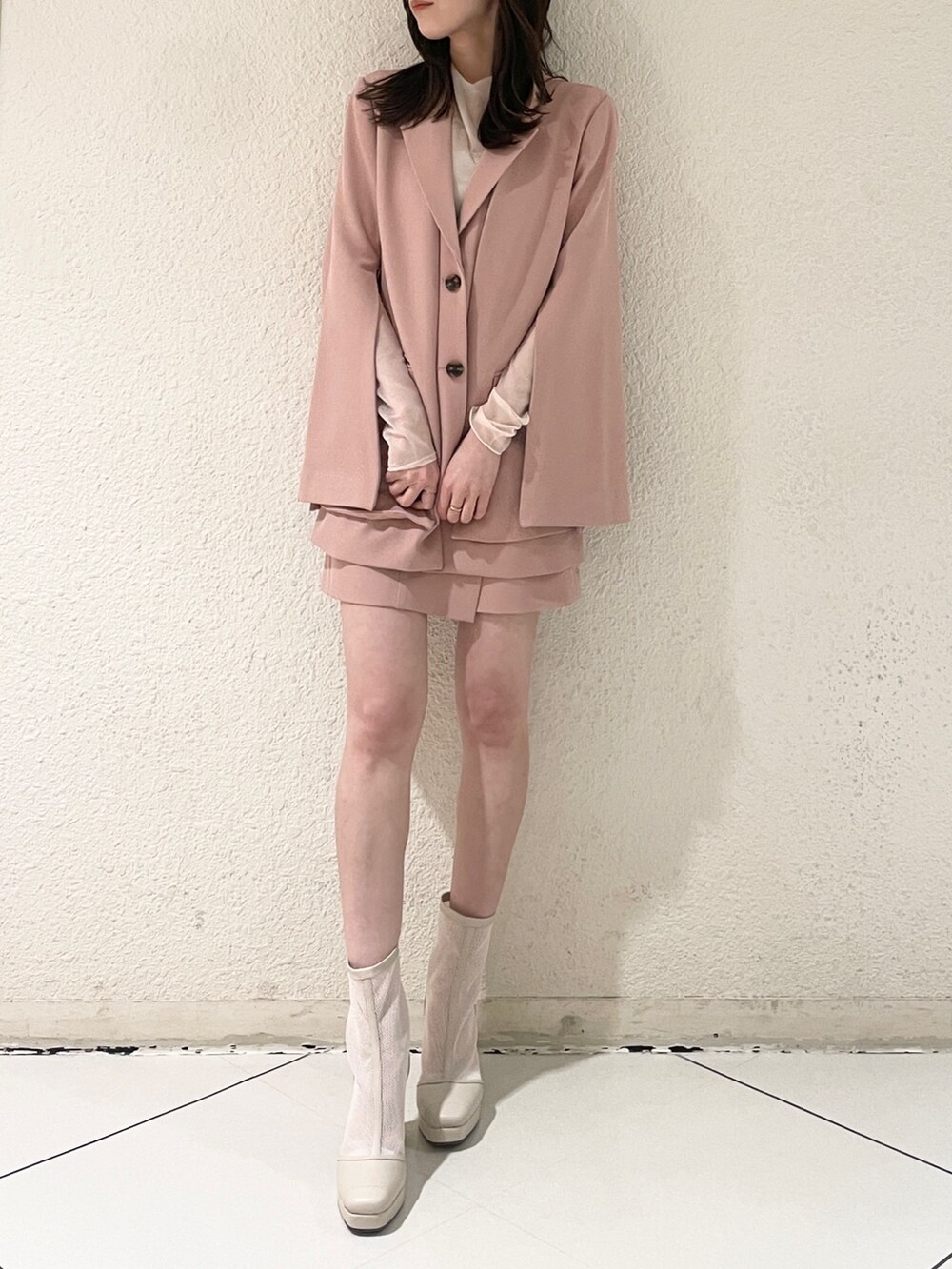 ピンク系のテーラードジャケット、ピンク系のスカート、ホワイト系のブーツを着用したレディースの冬コーディネートの5枚目の写真