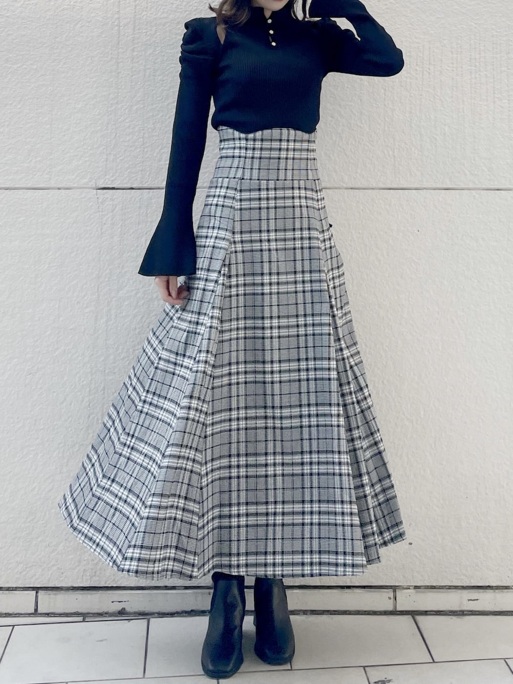 ブラック系のニット/セーター、グレー系のスカート、ブラック系のブーツを着用したレディースの秋コーディネートの3枚目の写真