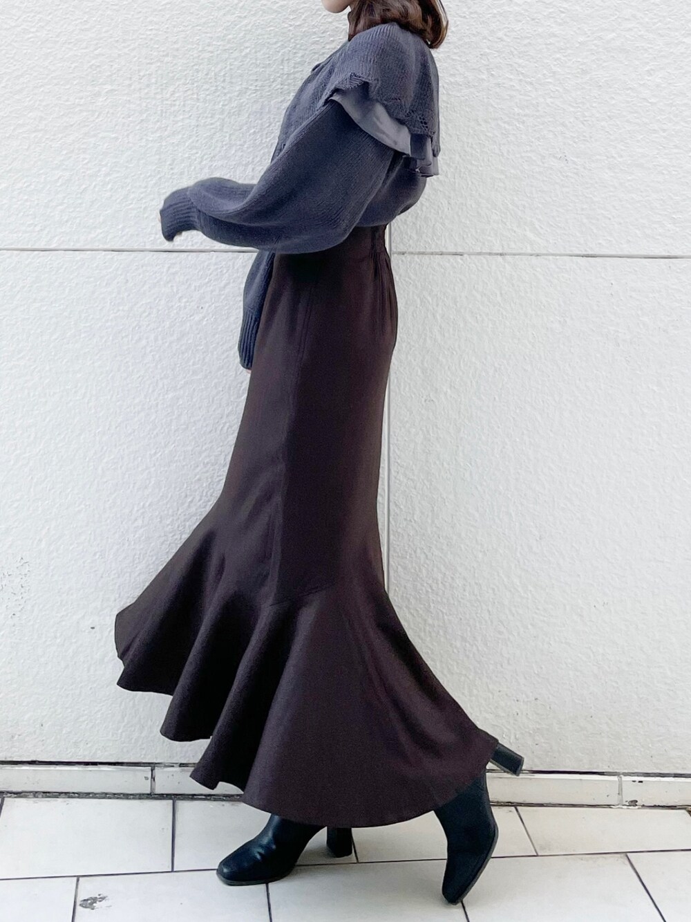 グレー系のニット/セーター、ブラウン系のスカート、ブラック系のブーツを着用したレディースの冬コーディネートの2枚目の写真