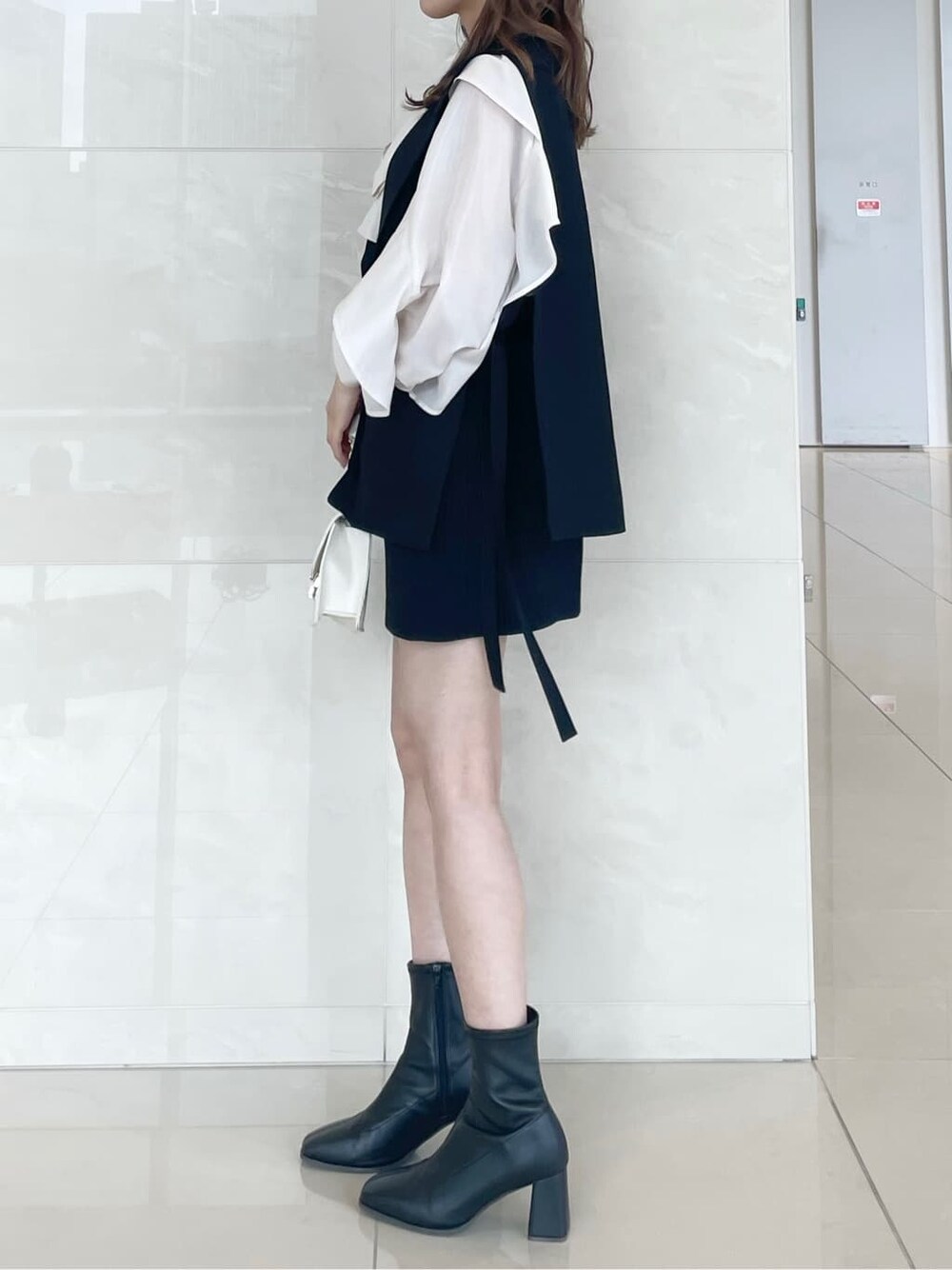 ホワイト系のシャツ/ブラウス、ブラック系のベスト、ブラック系のスカートを着用したレディースの秋コーディネートの3枚目の写真