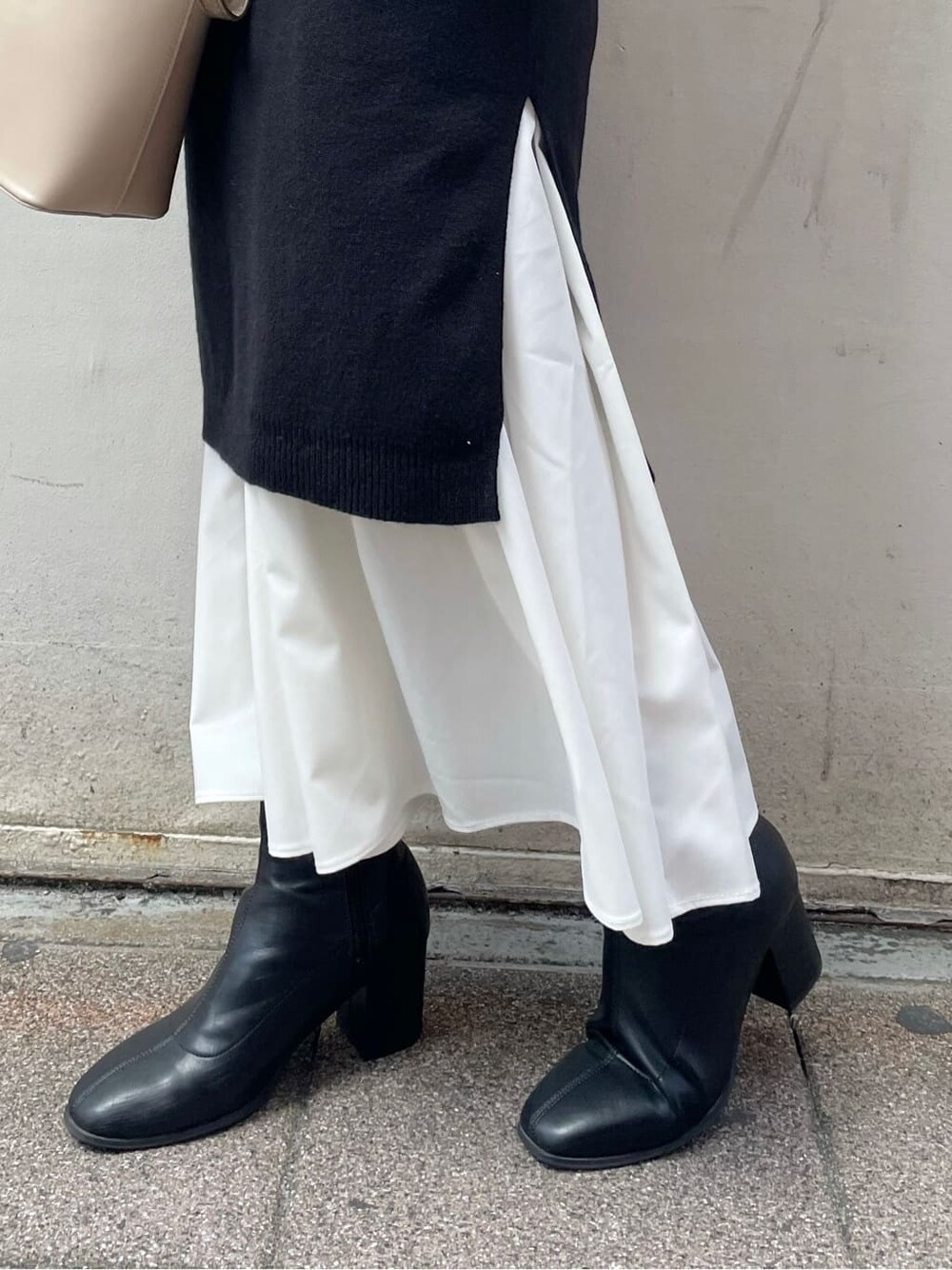 ブラック系のブーツ、ブラック系のワンピース、ベージュ系のハンドバッグを着用したレディースの秋コーディネートの10枚目の写真