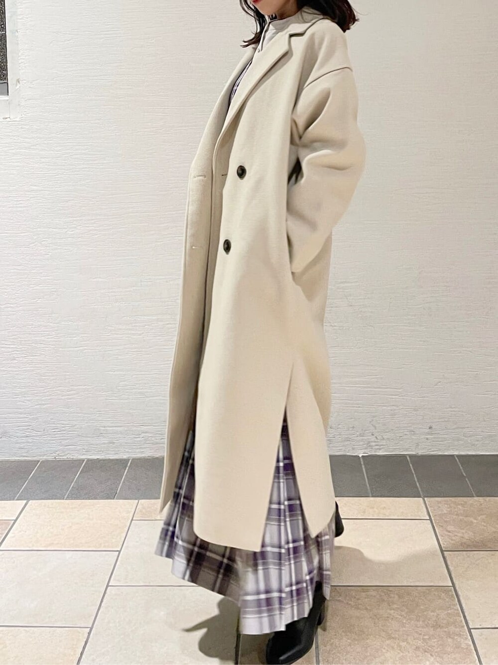 ブラック系のブーツ、ホワイト系のチェスターコート、パープル系のジャンパースカートを着用したレディースの冬コーディネートの2枚目の写真