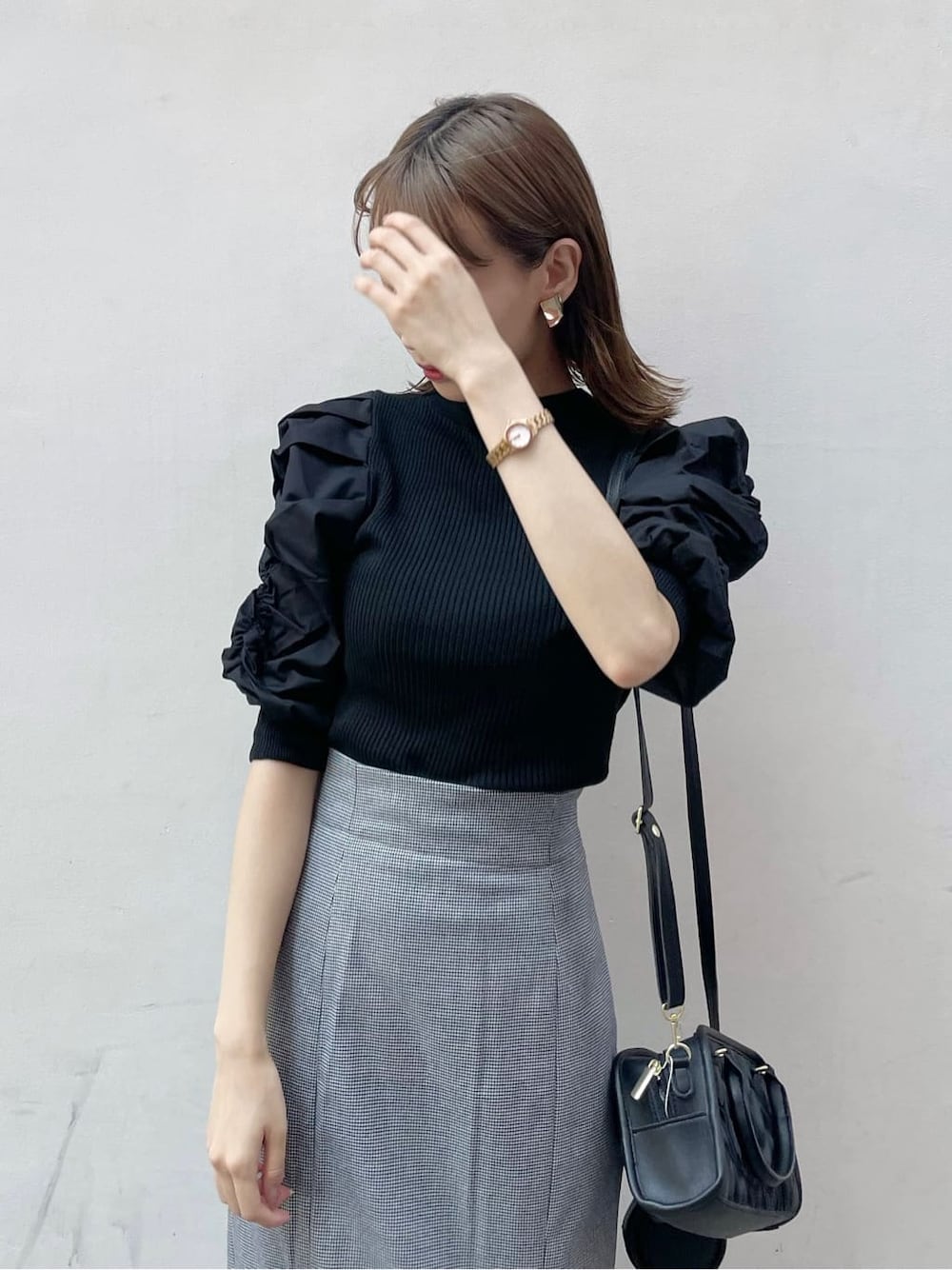 ブラック系のスカート、ブラック系のニット/セーター、ブラック系のハンドバッグを着用したレディースの秋コーディネートの4枚目の写真