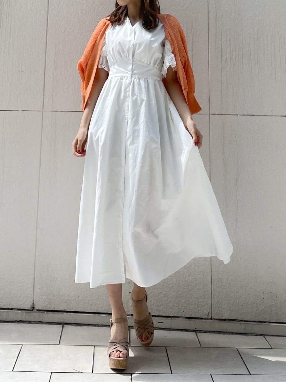 ホワイト系のワンピース、ベージュ系のサンダル、オレンジ系のカーディガン/ボレロを着用したレディースの春コーディネートの2枚目の写真