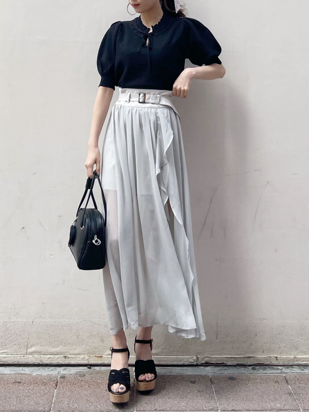 グレー系のスカート、ブラック系のサンダル、ホワイト系のニット/セーターを着用したレディースの春コーディネートの10枚目の写真