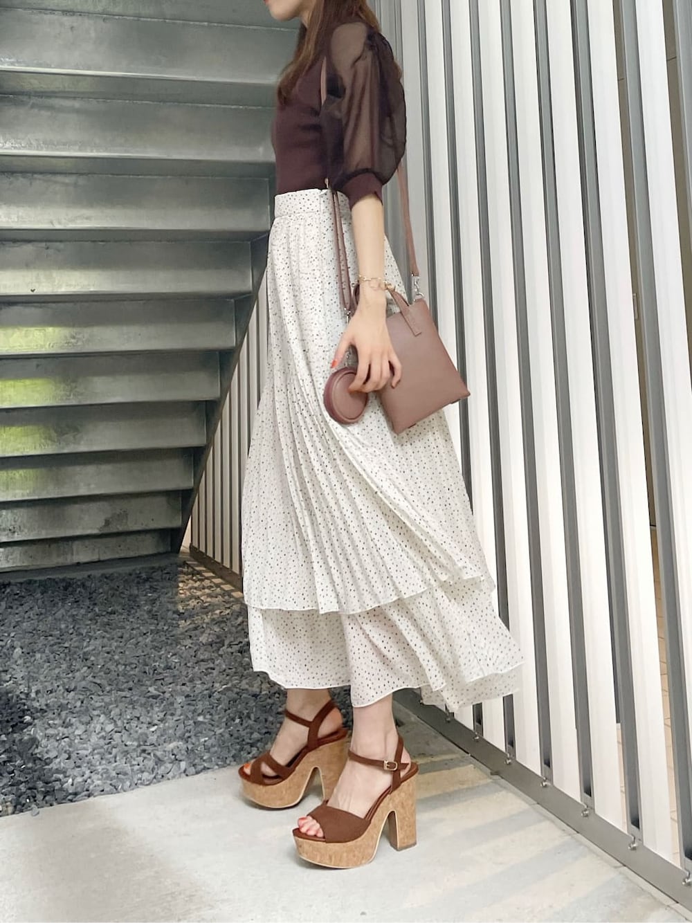 ブラウン系のサンダル、ブラウン系のハンドバッグ、ホワイト系のスカートを着用したレディースの夏コーディネートの4枚目の写真