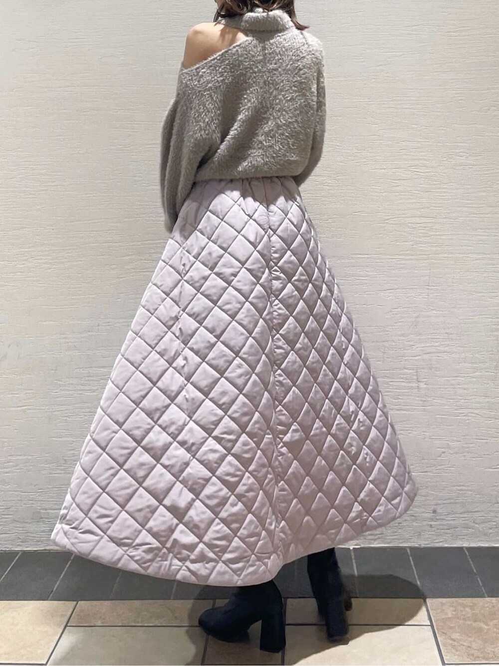 ピンク系のスカート、ブラック系のブーツ、ベージュ系のニット/セーターを着用したレディースの秋コーディネートの2枚目の写真