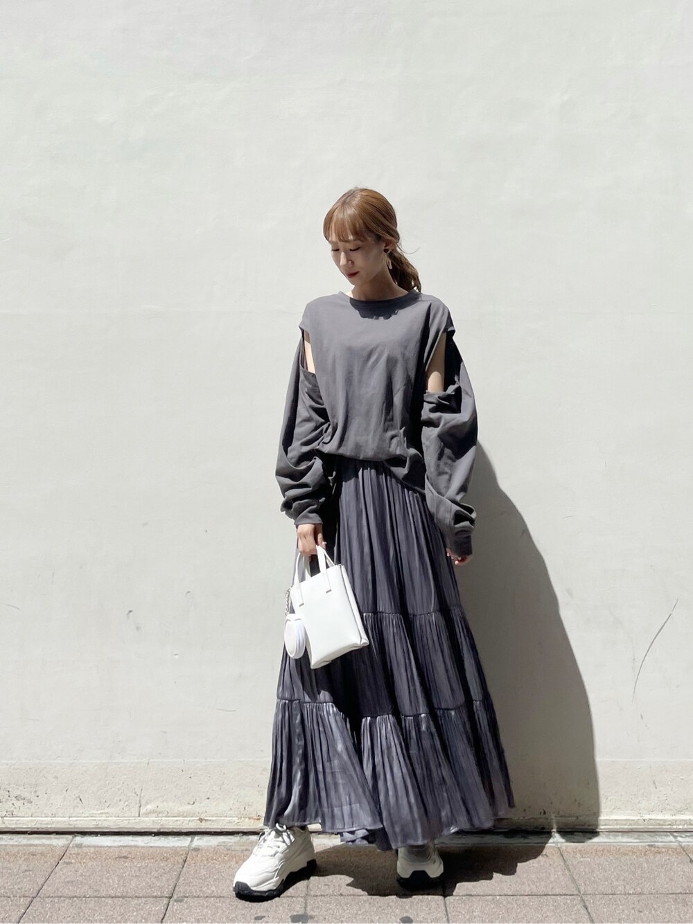 パープル系のスカート、ホワイト系のスニーカー、ホワイト系のハンドバッグを着用したレディースの春コーディネートの2枚目の写真