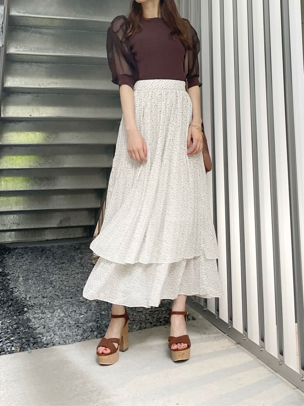 ブラウン系のサンダル、ブラウン系のハンドバッグ、ホワイト系のスカートを着用したレディースの夏コーディネートの2枚目の写真