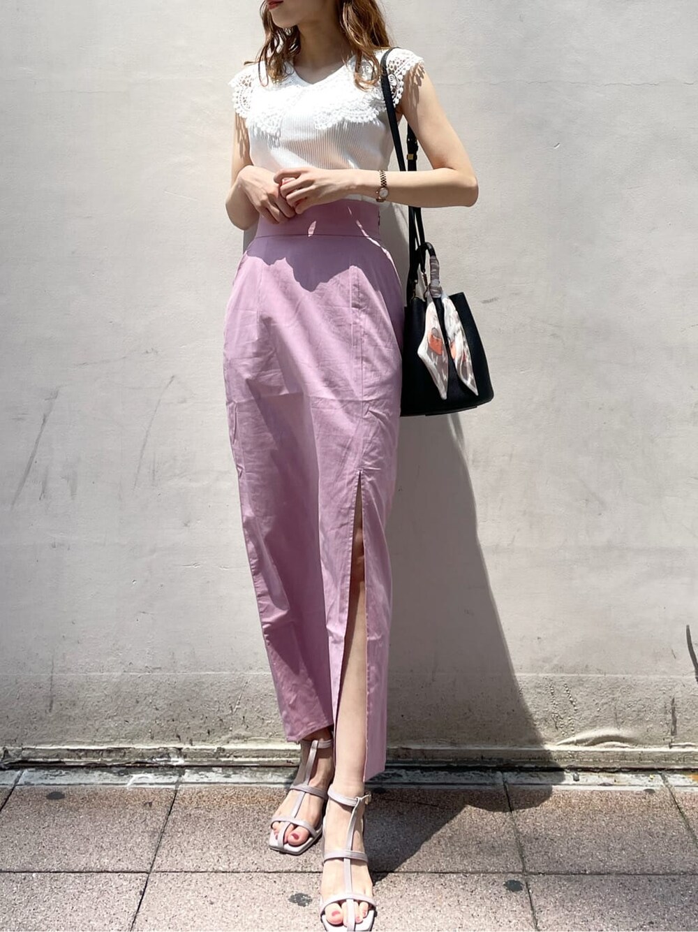 ブラック系のハンドバッグ、ピンク系のスカート、パープル系のサンダルを着用したレディースの夏コーディネートの2枚目の写真