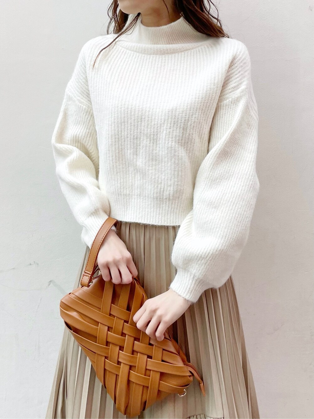 ブラウン系のクラッチバッグ、ホワイト系のニット/セーター、ブラウン系のブーツを着用したレディースの冬コーディネートの5枚目の写真