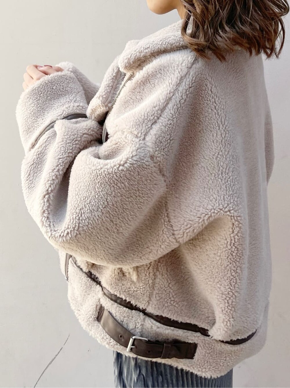 ベージュ系のブルゾン、ブラック系のブーツ、ブルー系のスカートを着用したレディースの秋コーディネートの3枚目の写真