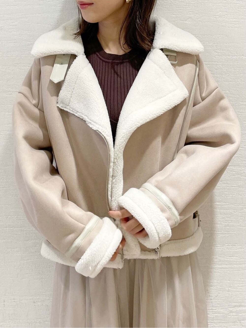 ベージュ系のスカート、ホワイト系のブルゾン、ブラウン系のニット/セーターを着用したレディースの夏コーディネートの4枚目の写真