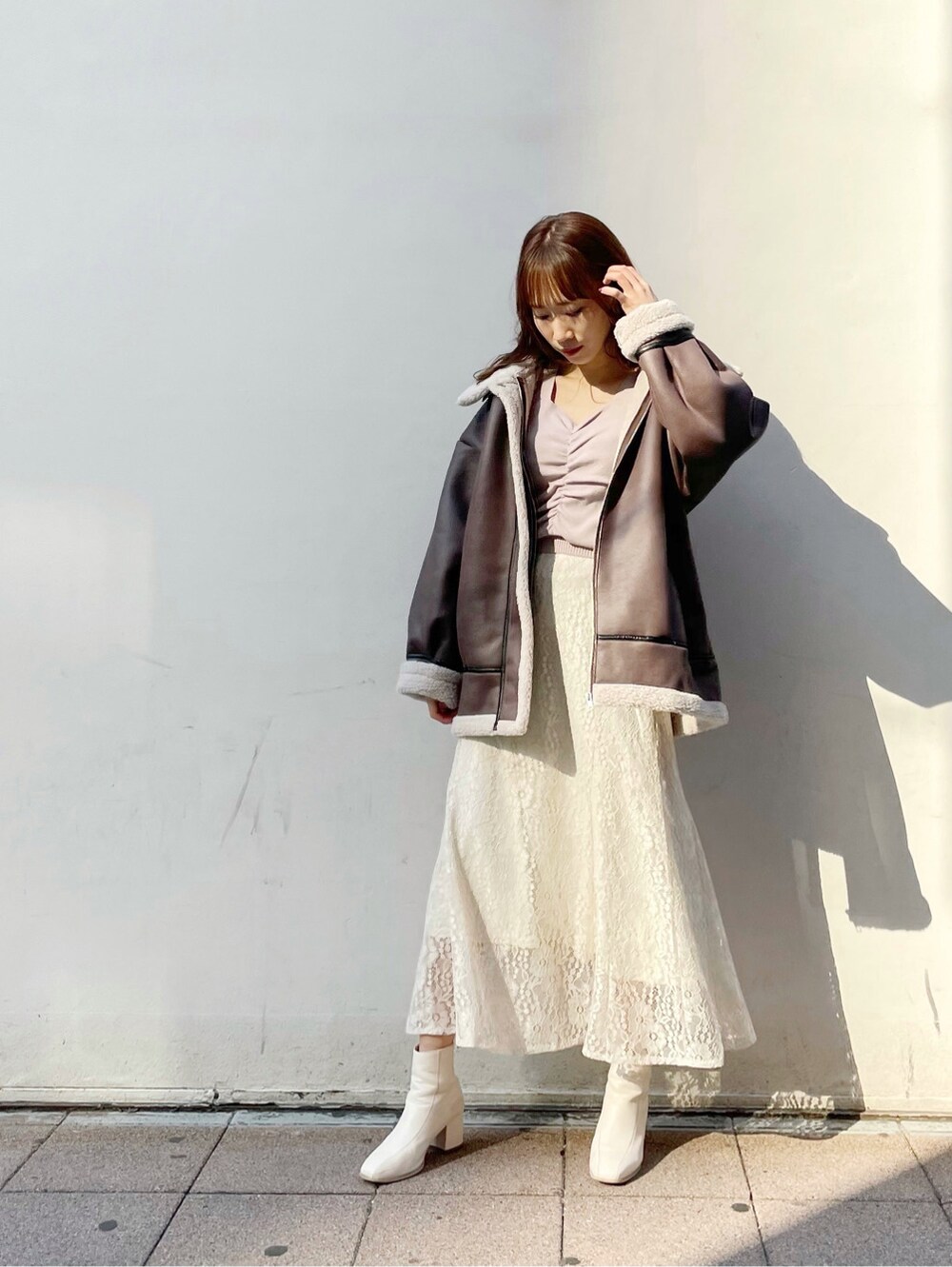 パープル系のニット/セーター、ホワイト系のブーツ、ホワイト系のスカートを着用したレディースの冬コーディネートの2枚目の写真