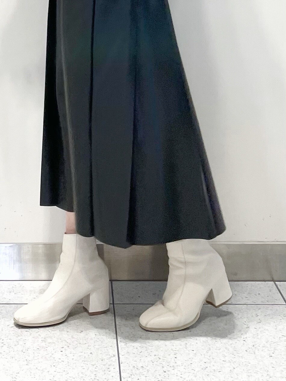 ホワイト系のブーツ、ブラック系のスカート、パープル系のニット/セーターを着用したレディースの冬コーディネートの4枚目の写真