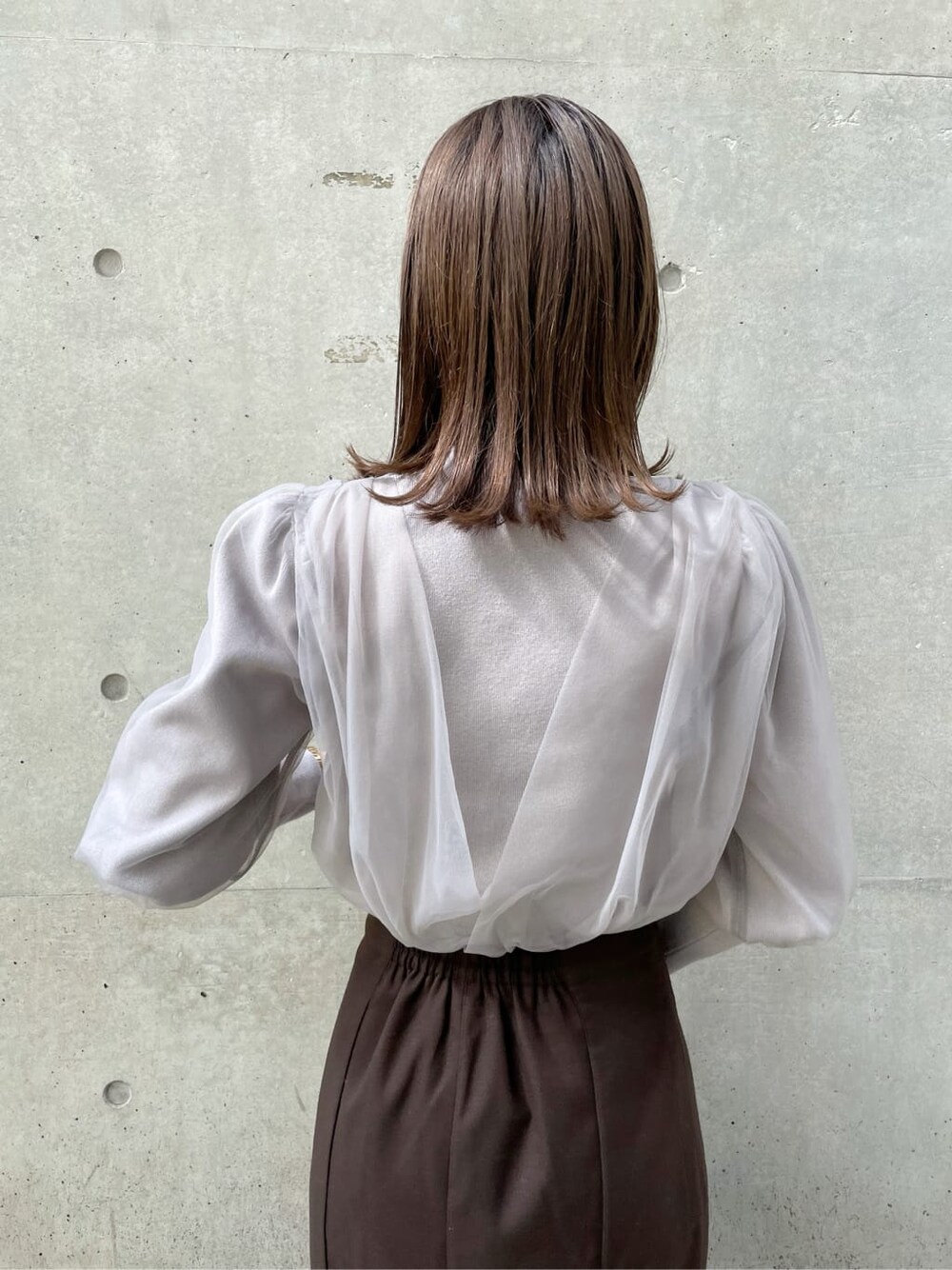 グレー系のニット/セーター、ブラック系のブーツ、ブラウン系のスカートを着用したレディースの秋コーディネートの6枚目の写真