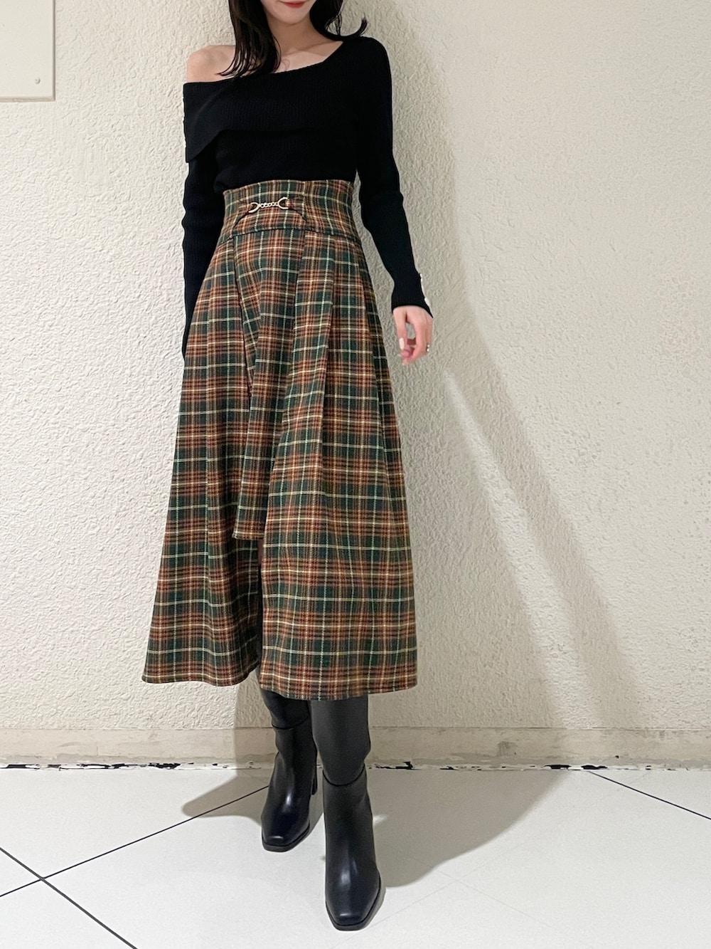ブラック系のニット/セーター、ブラック系のブーツ、グリーン系のスカートを着用したレディースの秋コーディネートの2枚目の写真