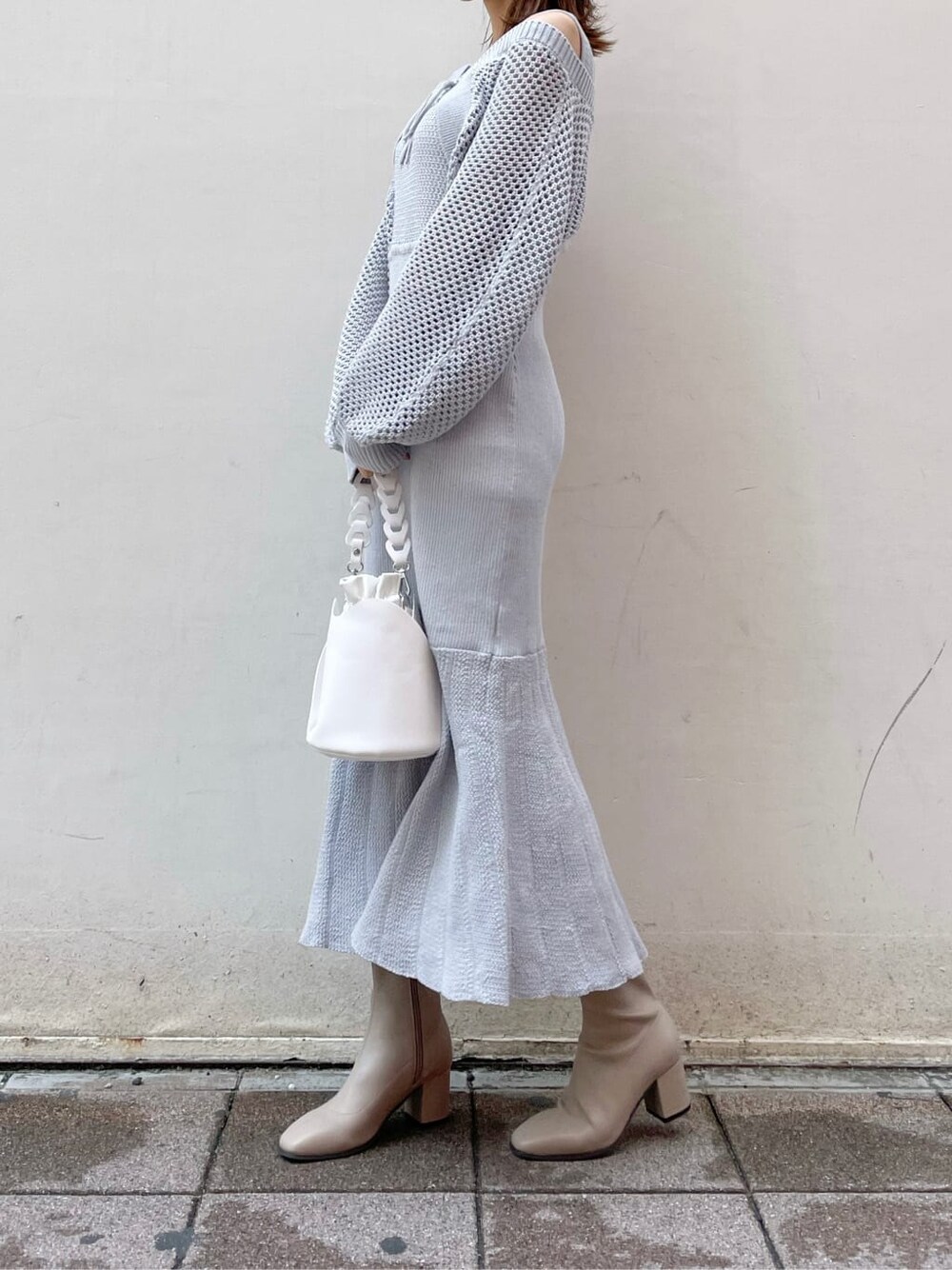 グレー系のワンピース、ホワイト系のハンドバッグ、ベージュ系のブーツを着用したレディースの秋コーディネートの2枚目の写真