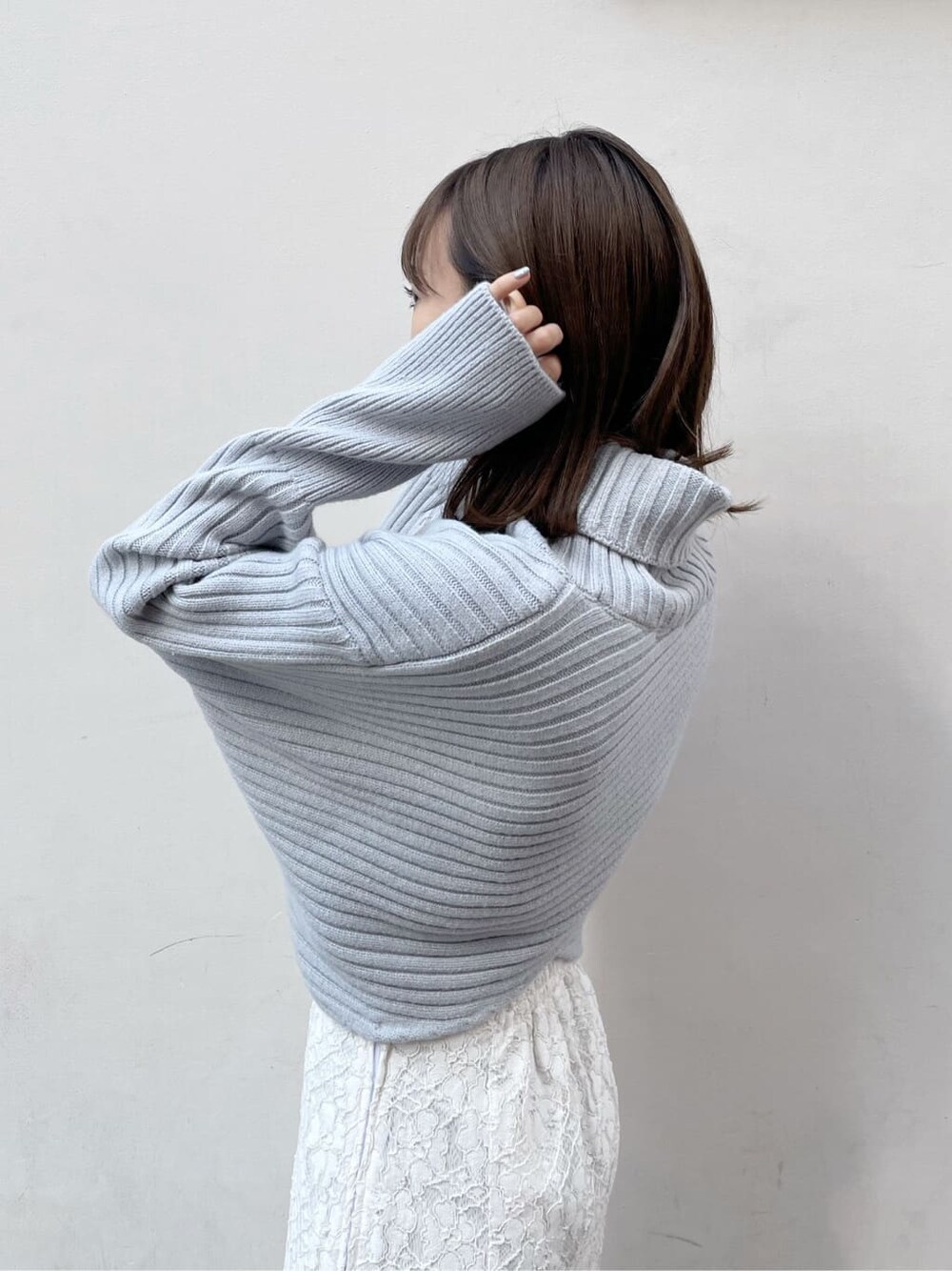 ホワイト系のスカート、ベージュ系のブーツ、ブルー系のニット/セーターを着用したレディースの秋コーディネートの5枚目の写真