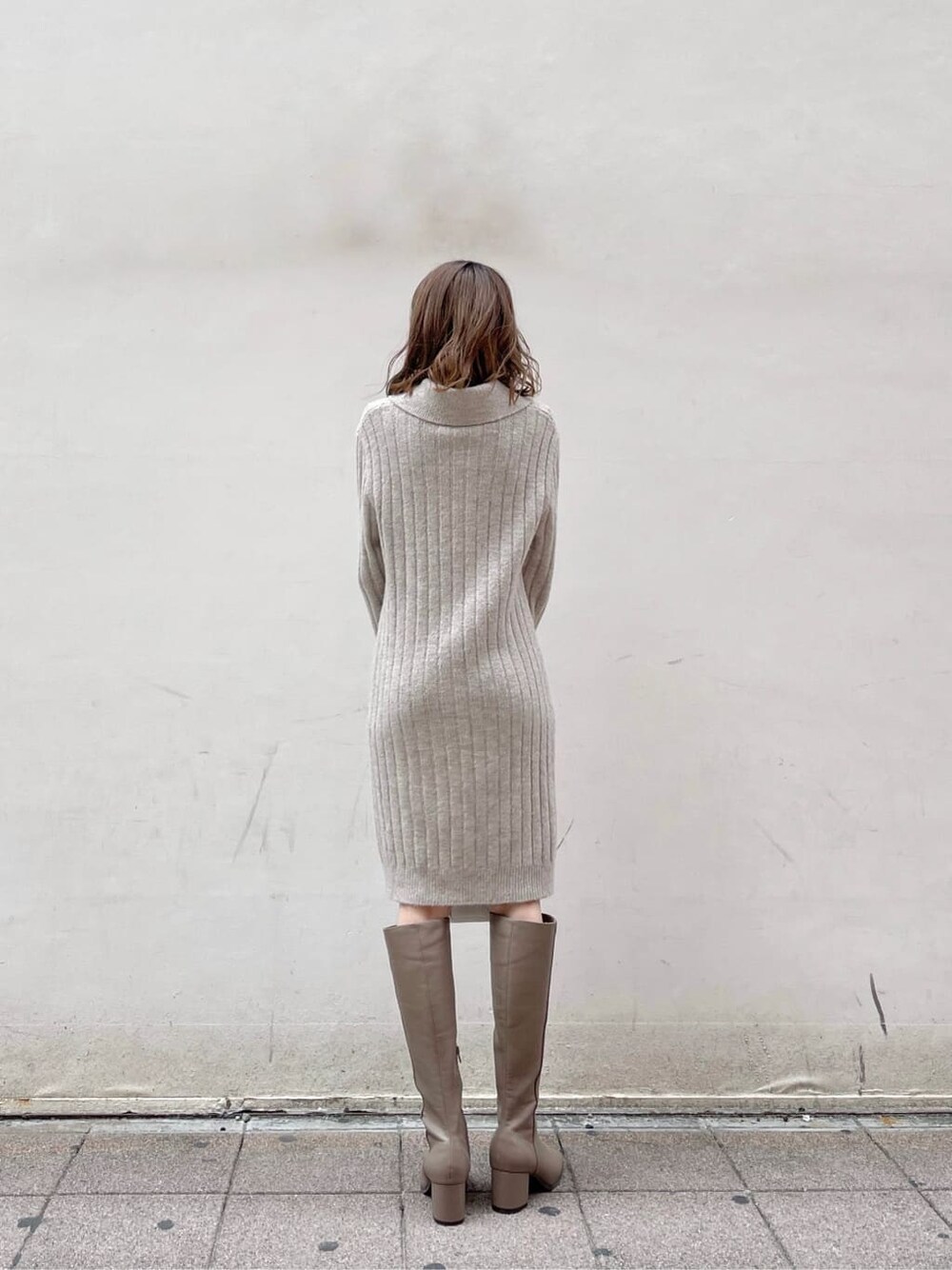 グレー系のワンピース、ホワイト系のハンドバッグ、ベージュ系のブーツを着用したレディースの秋コーディネートの3枚目の写真