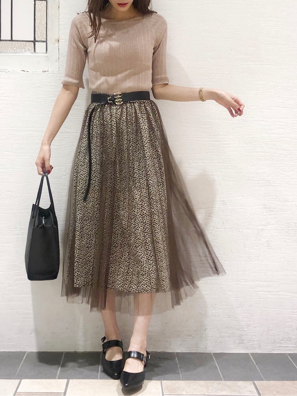 ピンク系のニット/セーター、ブラック系のパンプス、ブラウン系のスカートを着用したレディースの夏コーディネートの2枚目の写真