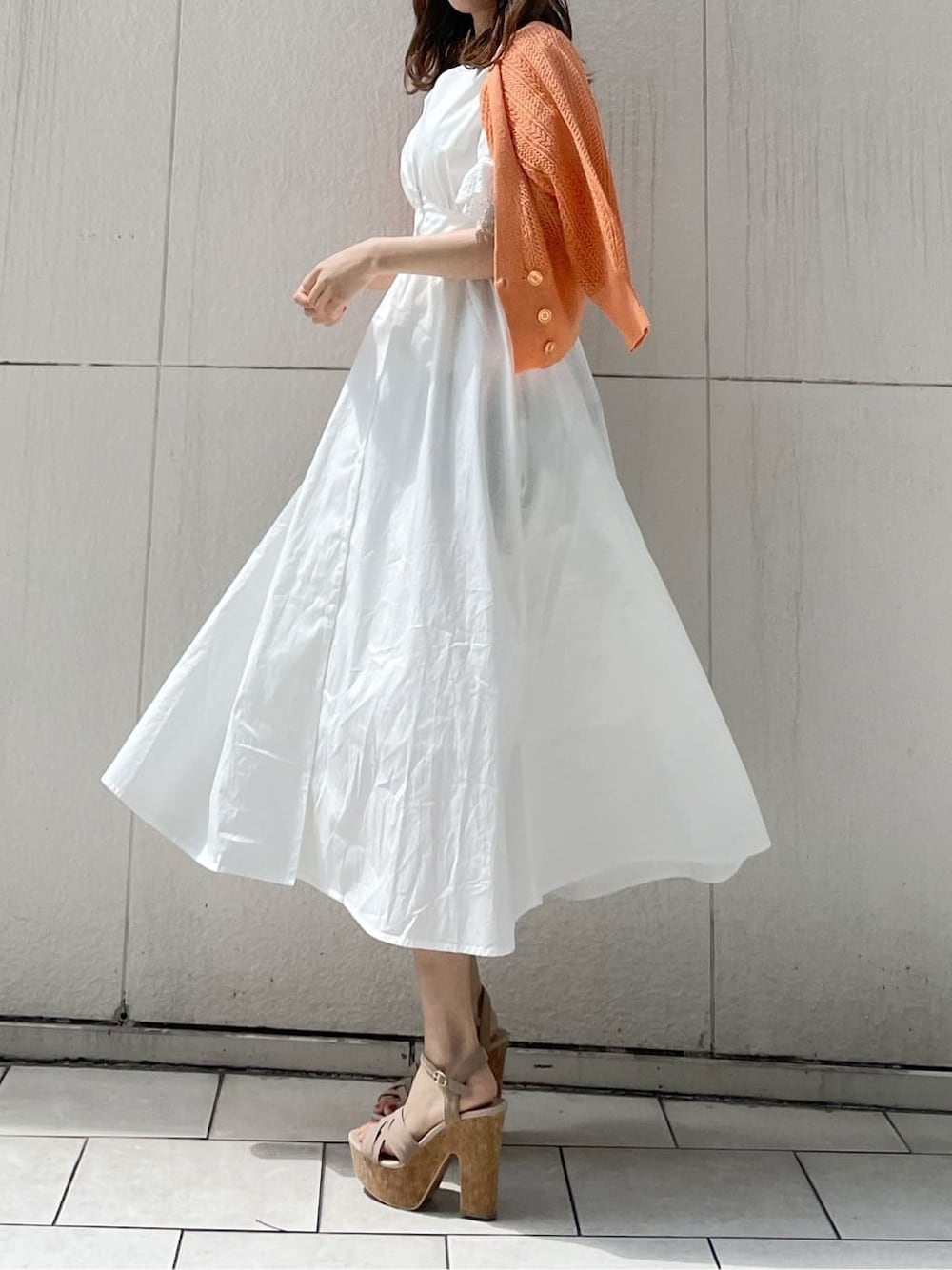 ホワイト系のワンピース、ベージュ系のサンダル、オレンジ系のカーディガン/ボレロを着用したレディースの春コーディネートの3枚目の写真