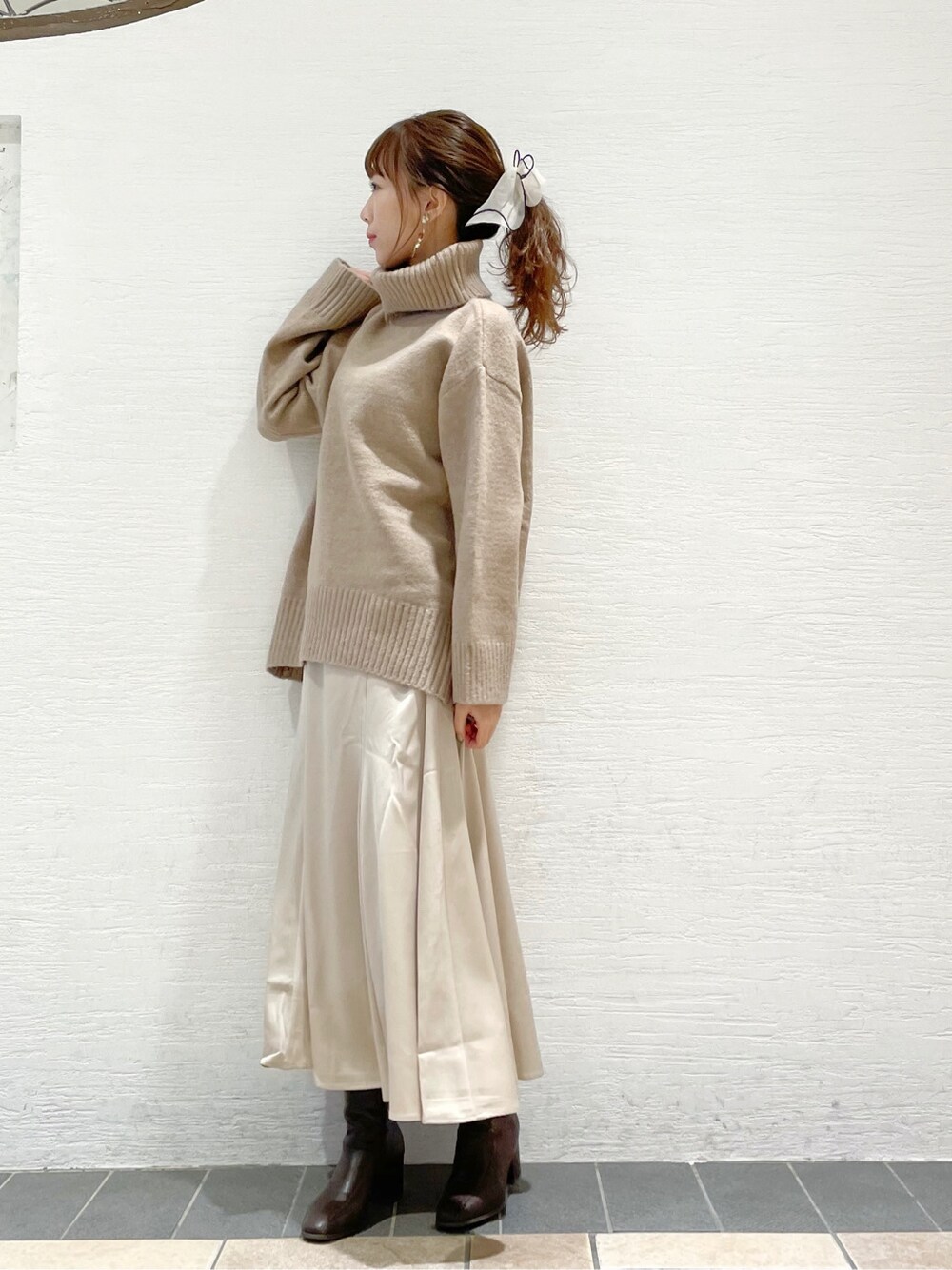 ブラウン系のブーツ、ホワイト系のスカート、ベージュ系のニット/セーターを着用したレディースの冬コーディネートの2枚目の写真